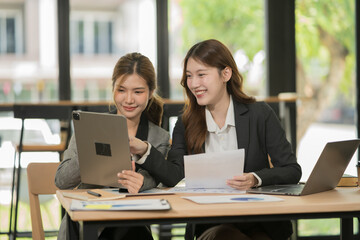 Asian businesswoman sitting in a meeting, talking about a document and chart placed on the table.