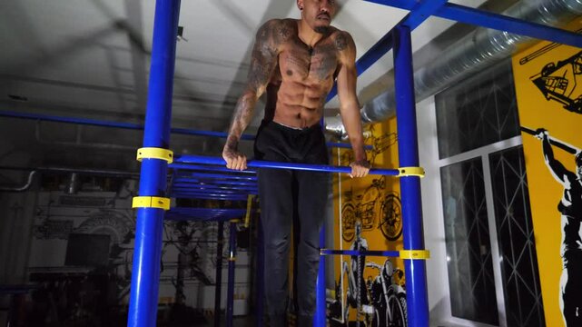 Strong african sportsman doing exercises on horizontal bar at modern gym. Muscular afro american man muscling up indoor. Young black athlete training at fitness club. Sport and active lifestyle - Powered by Adobe