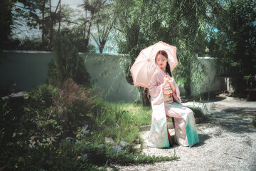 Young Woman in Kimono with Umbrella in Serene Japanese Garden
