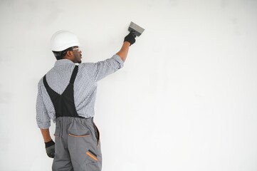 business, building, and people concept. african builder in hardhats with plastering tools indoors