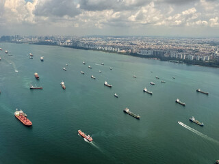 Ships navigating the waters near the coast with a city skyline in the background during a flight