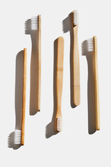 Eco-friendly wood toothbrushes with soft colorful bristles at sunlight on white background. Minimal design photo, sustainable hygiene concept, Zero waste lifestyle, eco-conscious living, hard shadow