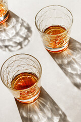 Crystal Glasses with drink, beautiful shadow at sunlight on beige textured background, minimal trend, aesthetic side view shiny glass, sun glare, strong alcohol drink concept, summertime,