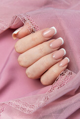 Woman showing french manicure on pink background with lace