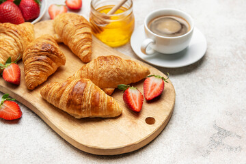 Delicious french breakfast with croissants, coffee, strawberries and honey