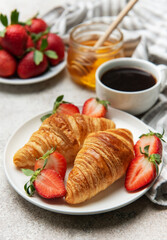 Delicious french breakfast with coffee, honey and croissants accompanied by fresh strawberries