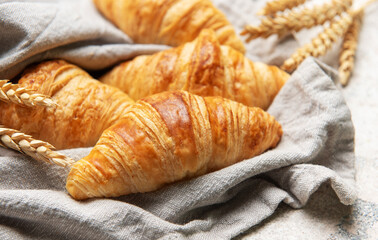 Freshly baked croissants resting on a linen cloth with wheat stalks