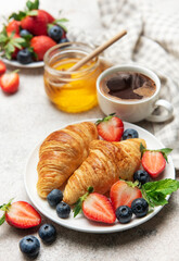 Delicious breakfast with croissants, coffee, berries and honey enjoying morning meal