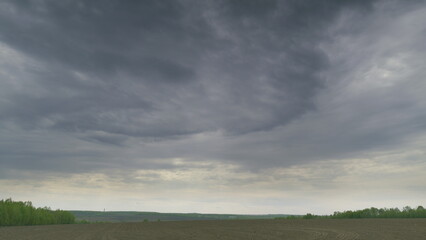 Obraz premium A Dramatic Cloudy Sky Over An Expansive Open Field Landscape That Captivates the Viewer