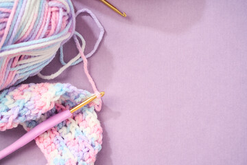 パステルカラーの毛糸でかぎ針編みをする編み物のイメージ