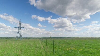 An Expansive Green Field with Power Lines Spanning Under a Dramatic Cloudy Sky Above Time lapse.
