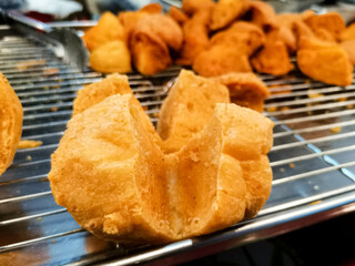Close up of golden crispy fried meatballs on a metal rack.
Hot fried snacks at asian street market.