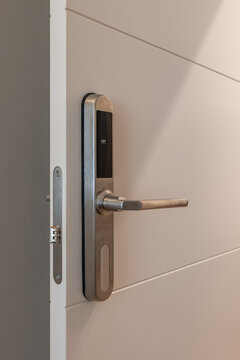 Close up of modern electronic door lock with stainless steel handle on white door in interior setting