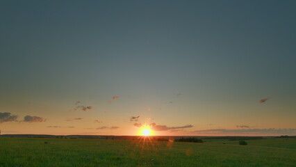 A Stunningly Beautiful Sunset Over an Expansive and Lush Grassland That Captivates the Eye