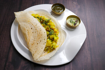 Crispy Masala dosa is a popular South Indian food item served with tomato chutney, coconut chutney, spicy potato masala, or aloo ki sabzi and sambar. Copy space. Crunchy Rice crepes.