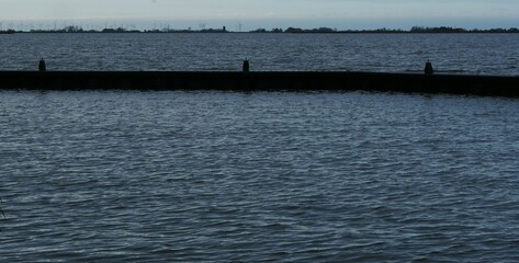 Narrow port wall at dusk in Oudega Friesland Netherlands, on the horizon many wind energy turbines. A politically controversial topic