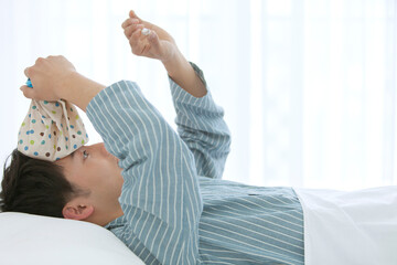 ベッドで体温を測るパジャマ姿の男性