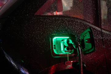 electric vehicle charging in rain with glowing green light. high-tech sustainability concept...
