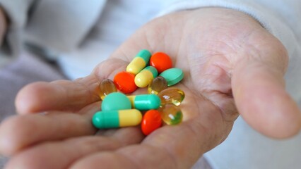 Close up view of a senior doctor's hand holding an assortment of colorful pills and capsules, highlighting the crucial role of medication in promoting health and wellness