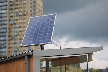solar panel on urban rooftop captures renewable energy against city skyline with overcast sky,...