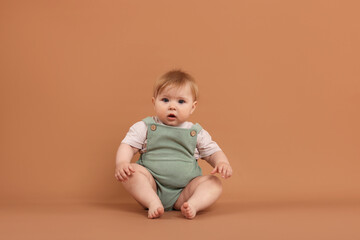 Naklejka premium Cute little baby on pale brown background