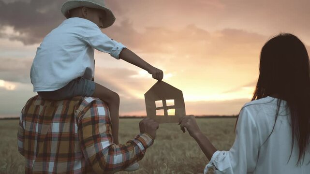 Family and home concept, man and woman with little son holding house symbol. Childhood and parenthood, happy moments of life, dream about country house, farmers family planning building own house