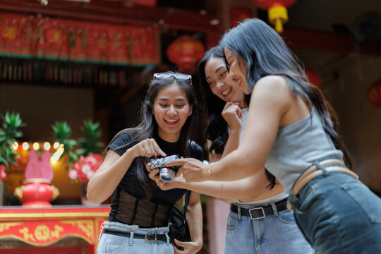 Tourists reviewing photos on digital camera inside chinese temple - Powered by Adobe