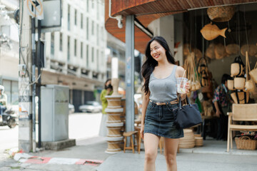 Young woman walking and drinking a refreshing beverage in bangkok