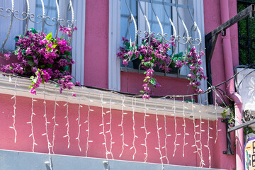Istanbul Balat Fassade eines rosafarben gestrichenen Hauses zu sehen, vor deren Fenstern &uuml;ppige Blumenk&auml;sten mit violett‑rosa Bl&uuml;ten stehen
