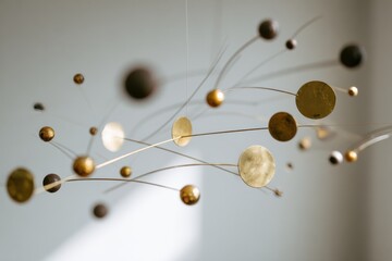 Obraz premium Delicate interplay of minimal brass mobile sculpture against a soft white backdrop enhancing spatial tranquility – commercial concept image