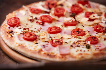 Pizza with ham, cherry tomatoes and mozzarella cheese. Wooden background. Soft focus. Close up.	