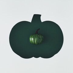 Creative autumn flat lay of decorative pumpkin visible through a pumpkin shaped gap. Cozy seasonal concept perfect for fall backgrounds, Thanksgiving themes and harvest celebrations. Top view banner.