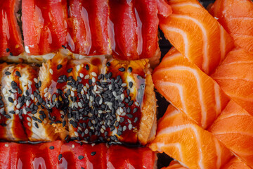 close up assortment of sushi rolls with salmon tuna and eel topped with sesame seeds and sauce