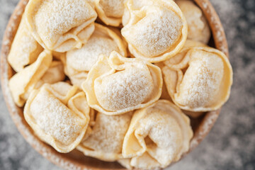 Wooden bowl filled with flour-dusted cappelletti pasta