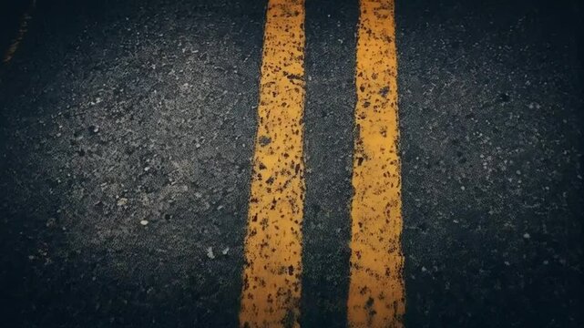 Road Marking: A close-up view of asphalt road with the distinct double yellow lines. This image captures the textures and patterns of the road's surface.