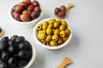 Variety of olives in bowls  on gray background, green olives, black and kalamata olives.