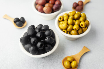Variety of olives in bowls  on gray background, green olives, black and kalamata olives.