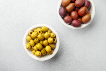 Variety of olives in bowls with wooden spoons on gray background, green olives, black and kalamata olives.