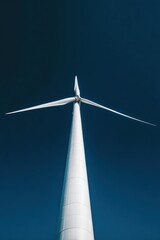 Impressive wind turbine rises against a pristine blue sky, embodying the essence of clean energy and minimalism