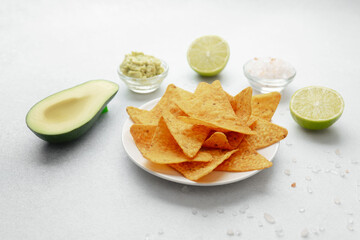 Nachos with avocado, guacamole, lime and salt on white table