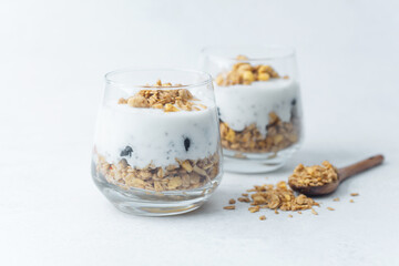 Yogurt parfait with granola and blueberries in glass cups