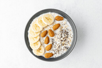 Banana almond chia oatmeal bowl with milk on bright white table
