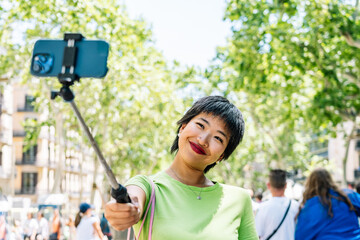 Tourist taking selfie with smartphone and selfie stick in barcelona