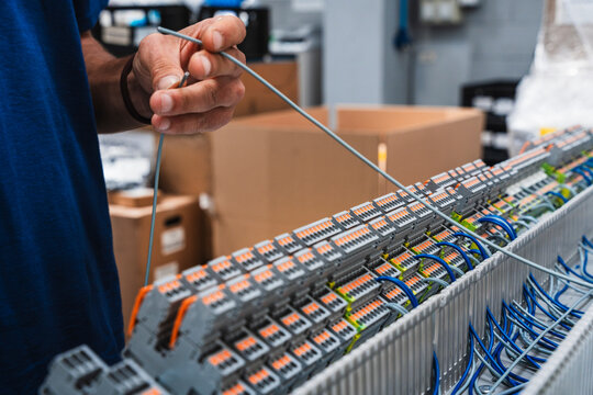 Technician hands working with electrical wiring in control panel in workshop