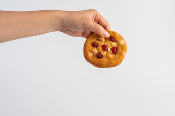 Vanilla cookies topped with nuts and strawberries and hand on a white background