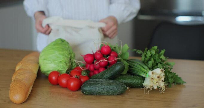Woman put a bag of groceries on the kitchen table. Women hands put vegetables and and fruits on the table.