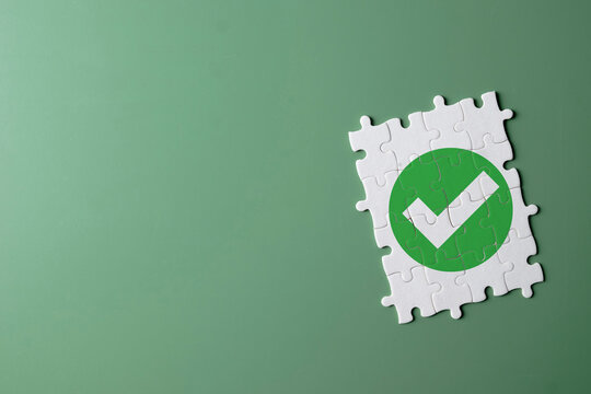 A completed jigsaw puzzle with a green checkmark icon on green background.,Concept for quality assurance (QA),ISO certification,achieving a goal,validation, correct data,standard,positive result.