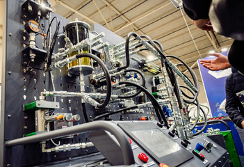 Detail of complex industrial hydraulic or pneumatic system test bench with hoses, valves, gauges, fluid reservoir, and control panel. Technology and engineering.