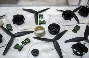 Assortment of plastic components, including drone propellers, buckles, and molded parts, displayed...