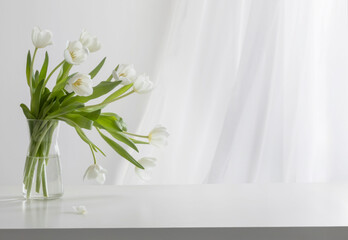 white tulips in glass vase in white interior